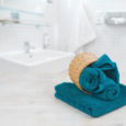 Green-blue folded towels in wicker basket over defocused bathroom