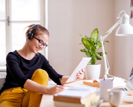 A young female student sitting at the table, using tablet when studying.