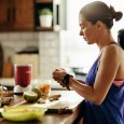 Athletic woman slicing fruit while preparing smoothie in the kitchen.