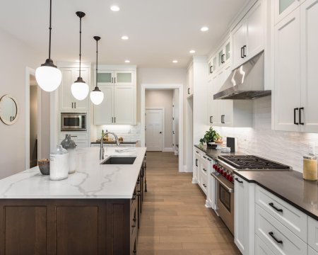 beautiful kitchen in new luxury home with island, pendant lights, and glass fronted cabinets