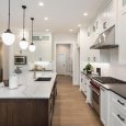 beautiful kitchen in new luxury home with island, pendant lights, and glass fronted cabinets