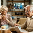 Happy senior woman drinking coffee and talking to her husband during breakfast.