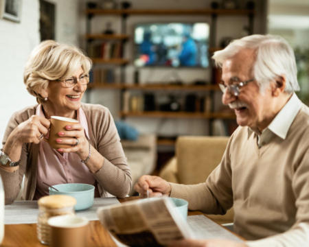 Happy senior woman drinking coffee and talking to her husband during breakfast.