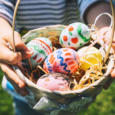 Colorful Easter eggs in basket. Children gathering painted decoration eggs in spring park. Kids hunt for egg outdoors.