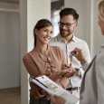 Young happy couple receiving keys of their new home from real estate agent.