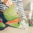 woman's hand pouring green smoothie into a glass