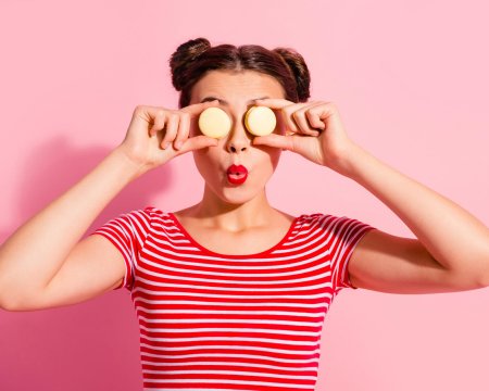 Close-up portrait of her she nice cute attractive glamorous funny cheerful cheery girl wearing striped t-shirt covering closing eyes with colorful snacks isolated over pink pastel background