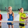 Joyful pupils learning to play tennis