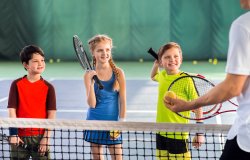 Joyful pupils learning to play tennis