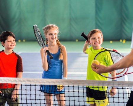 Joyful pupils learning to play tennis